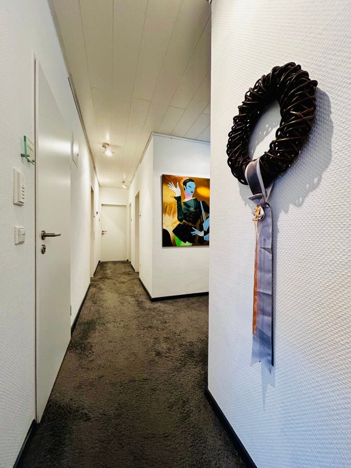 Flur Langer Flur mit einer Wanddekoration in Form eines Kranzes und einem Gemälde.