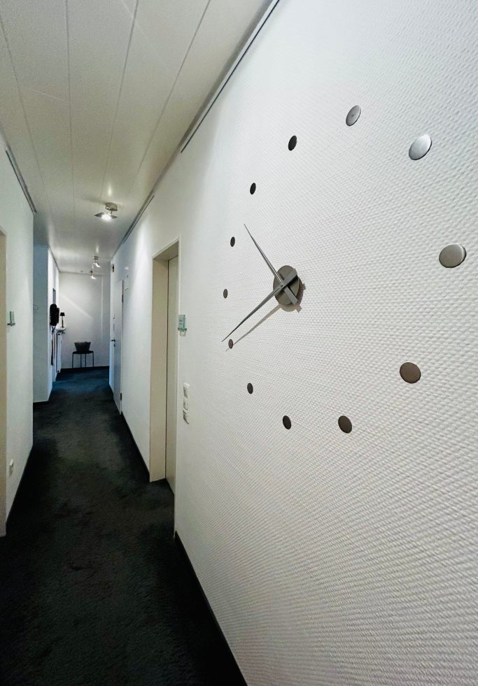 Flur 3 Wand mit einer modernen Uhr und einem langen Flur im Hintergrund.