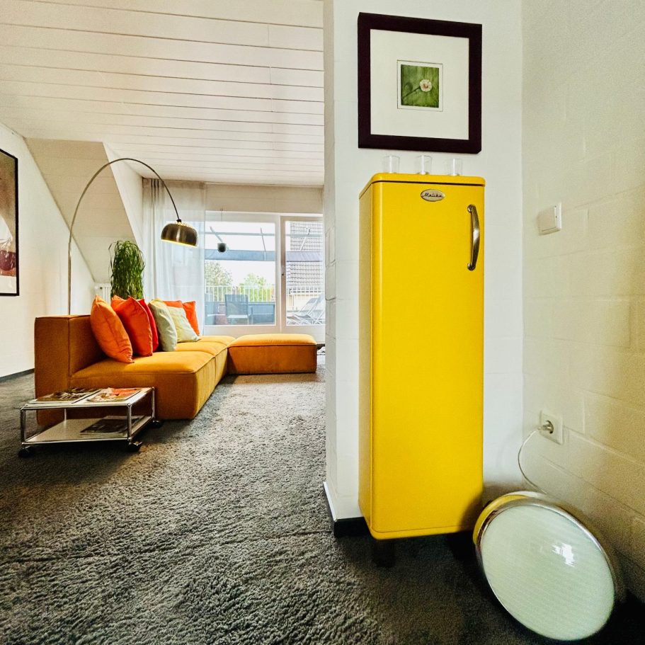 Frische & Liebe zum Detail Gelber Malibu Schrank in modernem Wohnzimmer mit orangefarbenem Sofa und Pflanzen.