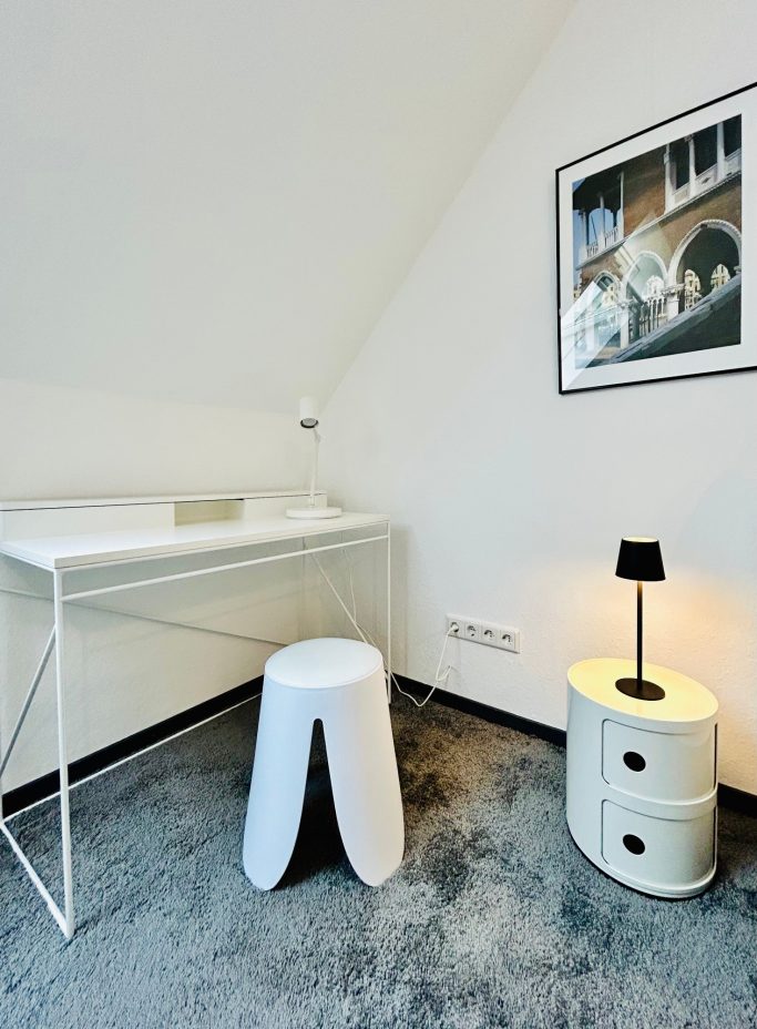 Familienzimmer 3 Moderne Ecke mit Schreibtisch, Hocker und einer Lampe neben einem Bild an der Wand.