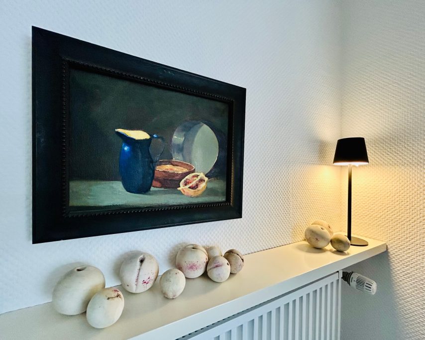 Kunstwerk Stillleben mit blauer Kanne, Brot und dekorativen Objekten auf einem Regal.